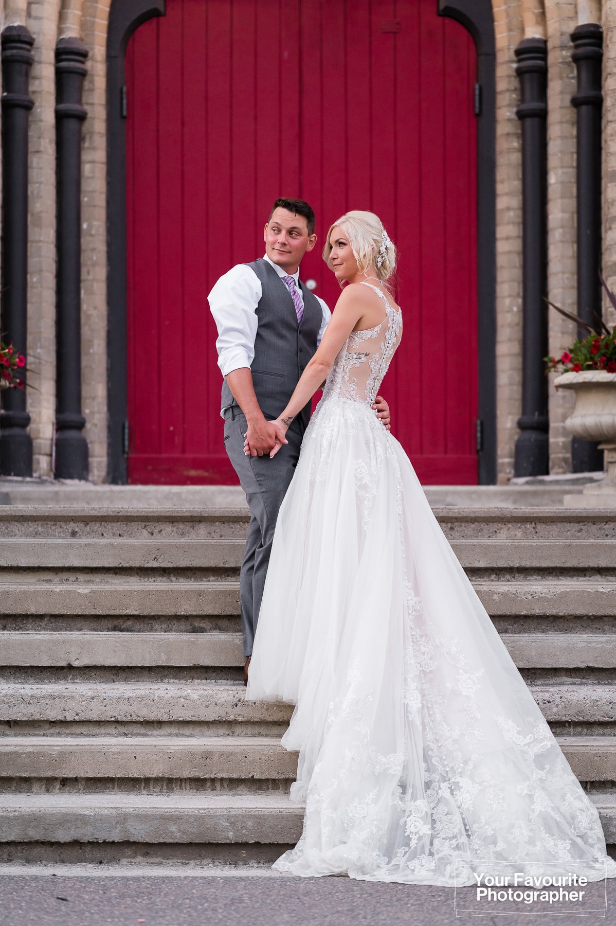 Bride and groom pose in front of the red door at Millbrook Cathedral