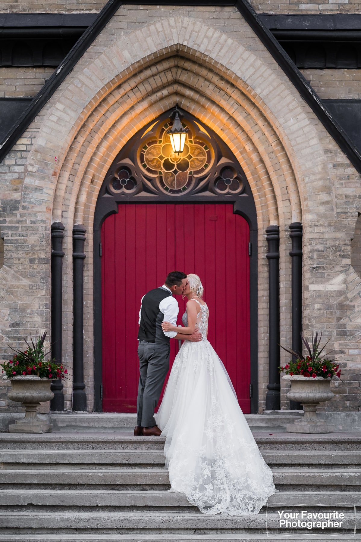 Bride and groom pose in front of the red door at Millbrook Cathedral