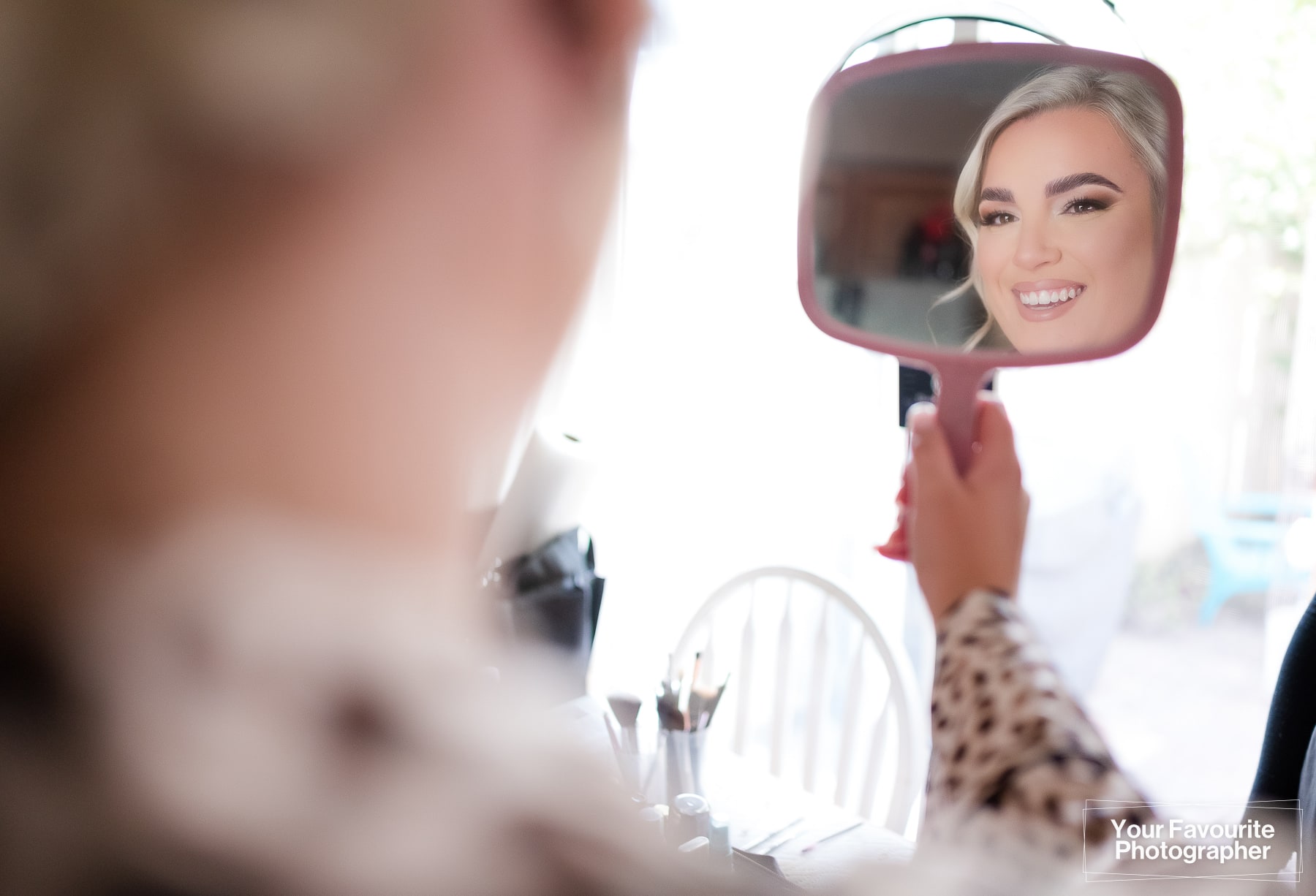 Bride admires her makeup in the mirror