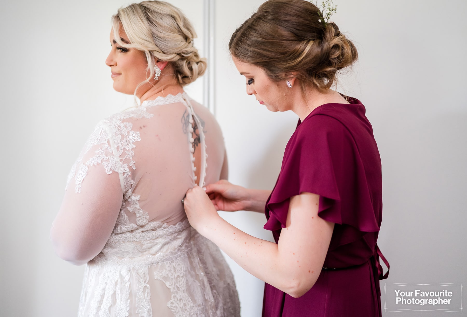 Bridesmaid helps with the wedding dress