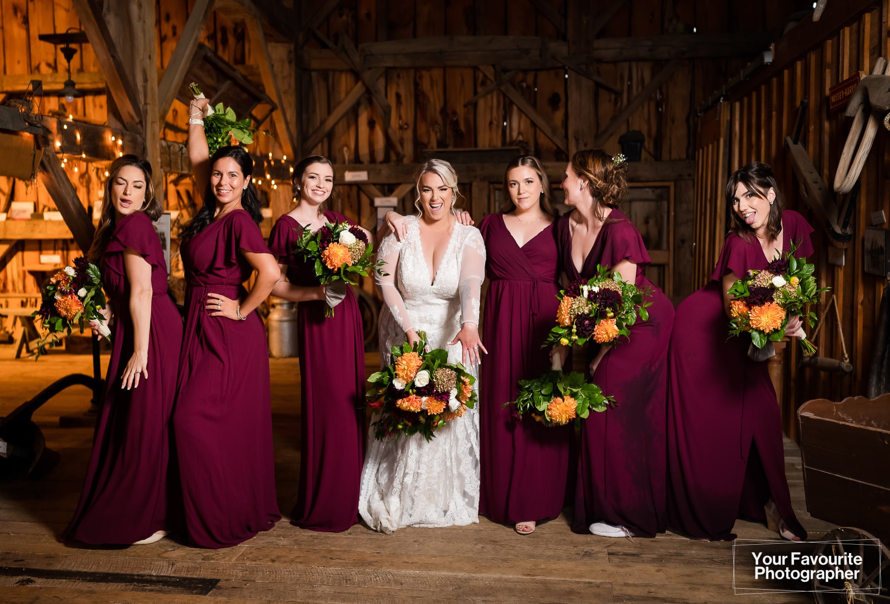 Wedding party photographed indoors in a barn, wearing burgundy