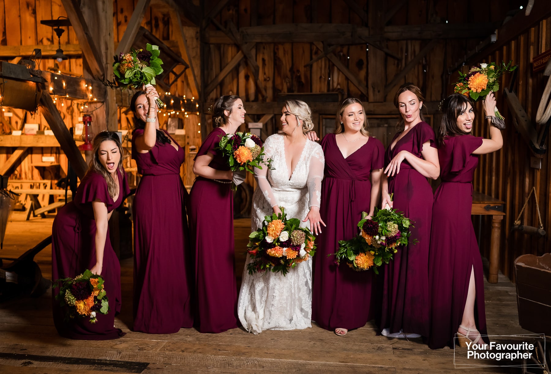 Wedding party photographed indoors in a barn, wearing burgundy