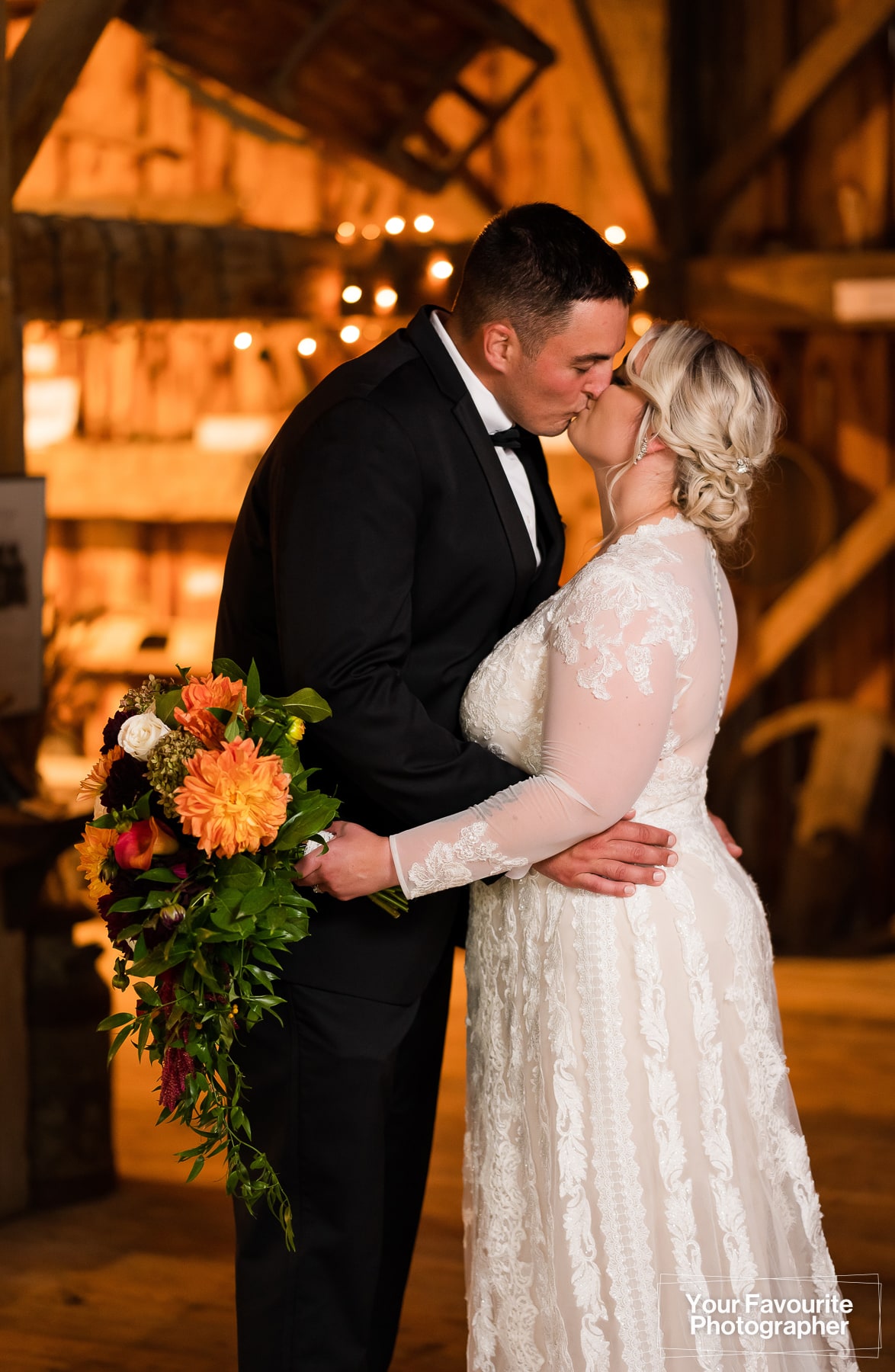 Bride and groom kissing in a barn
