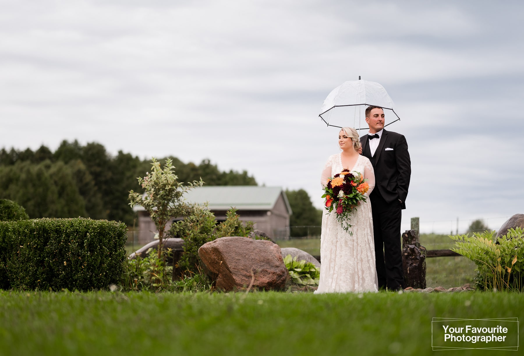 Bride and groom standing in the rain on a farm