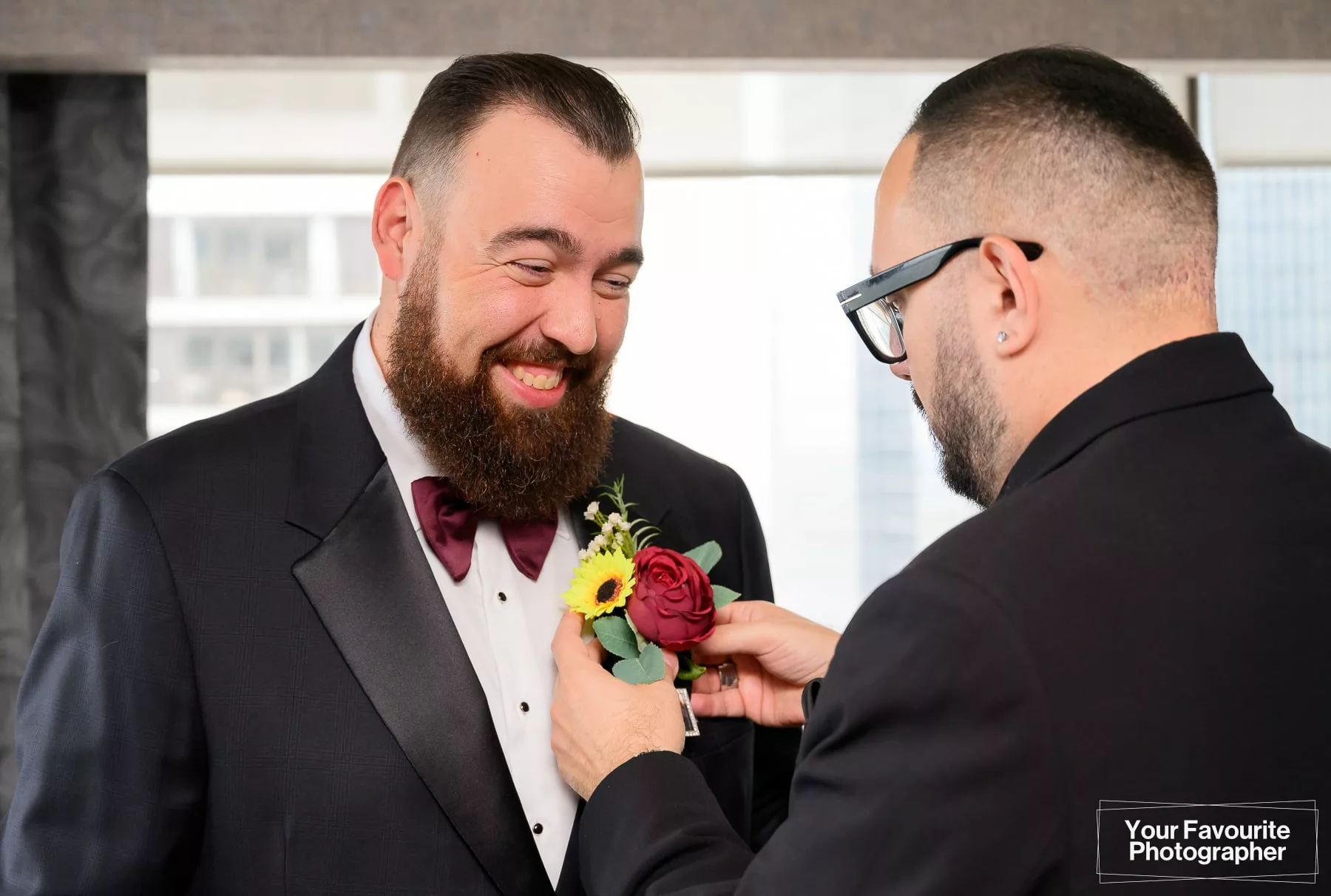 Groom getting his boutonniere placed on his suit jacket