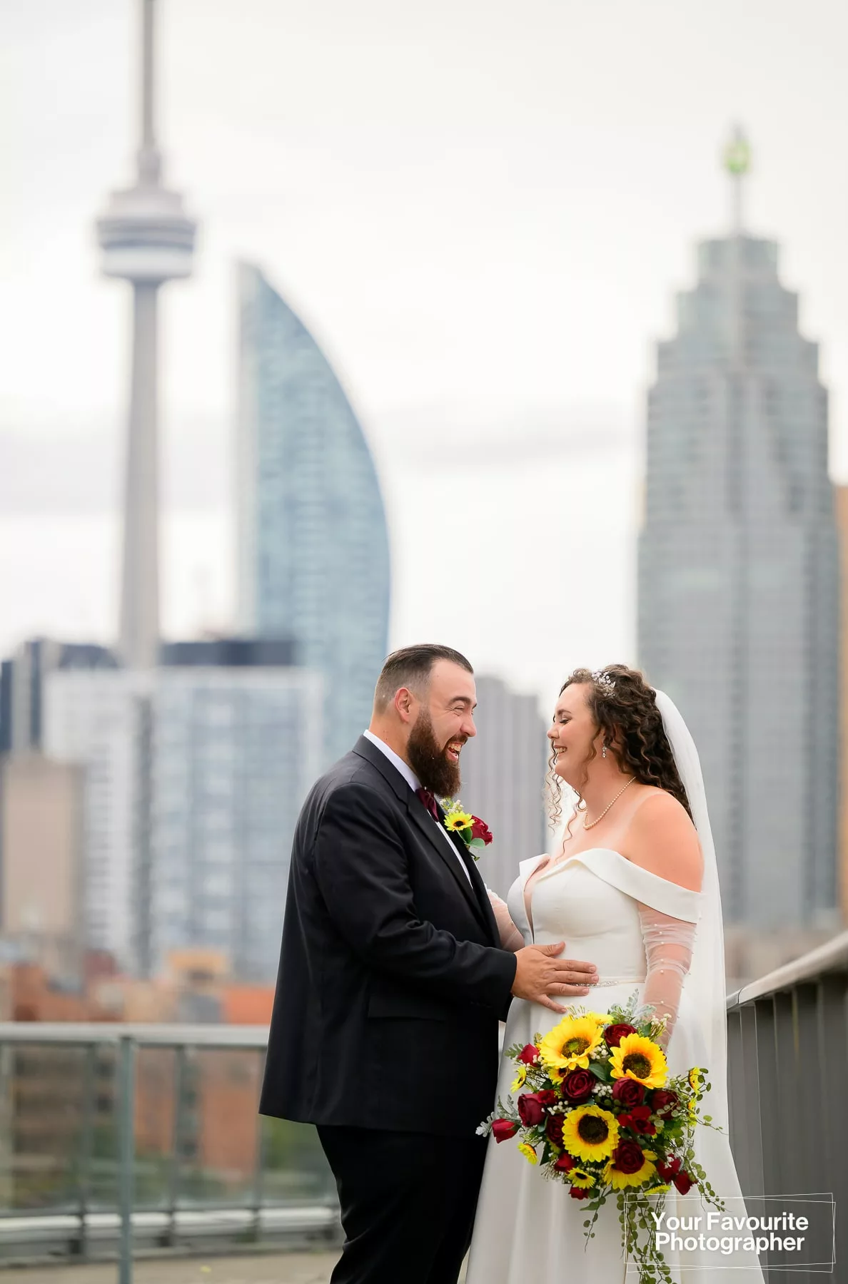 Bride and groom Emily and Niko pose on a rooftop patio with the skyline of downtown Toronto visible in the background