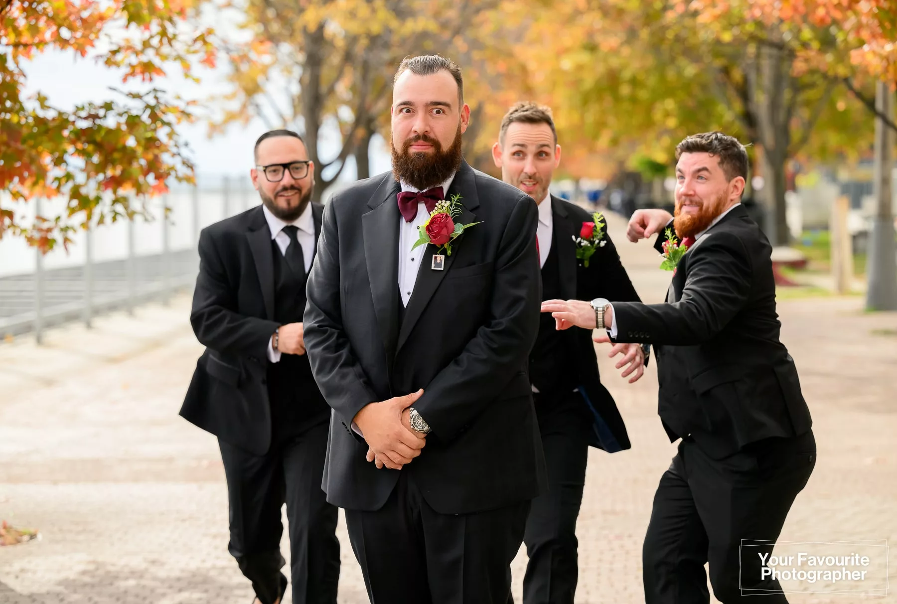 Photo of a groom with his groomsmen running towards him, about to attack