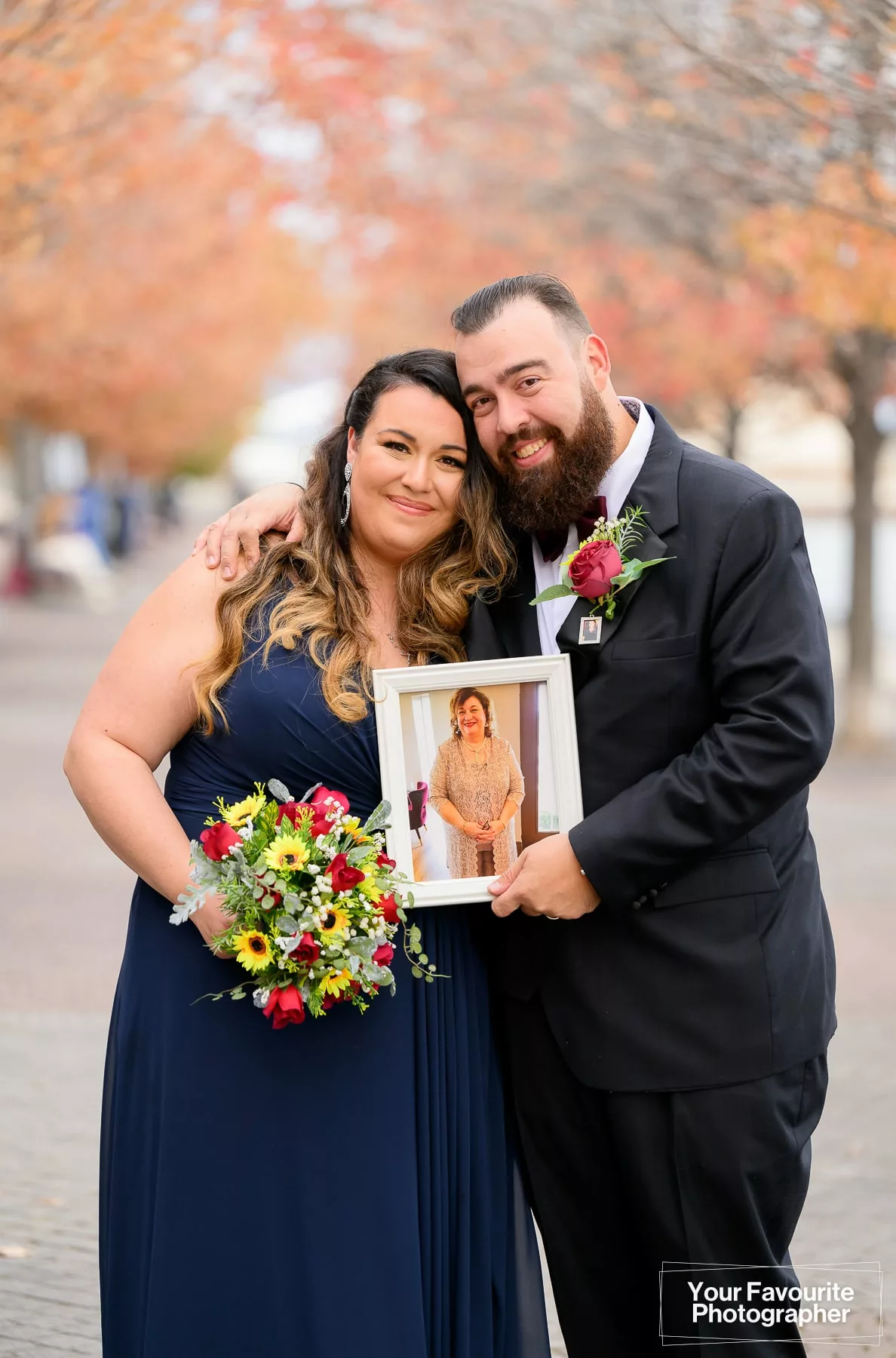 Groom and his sister pose with a photo of their mother