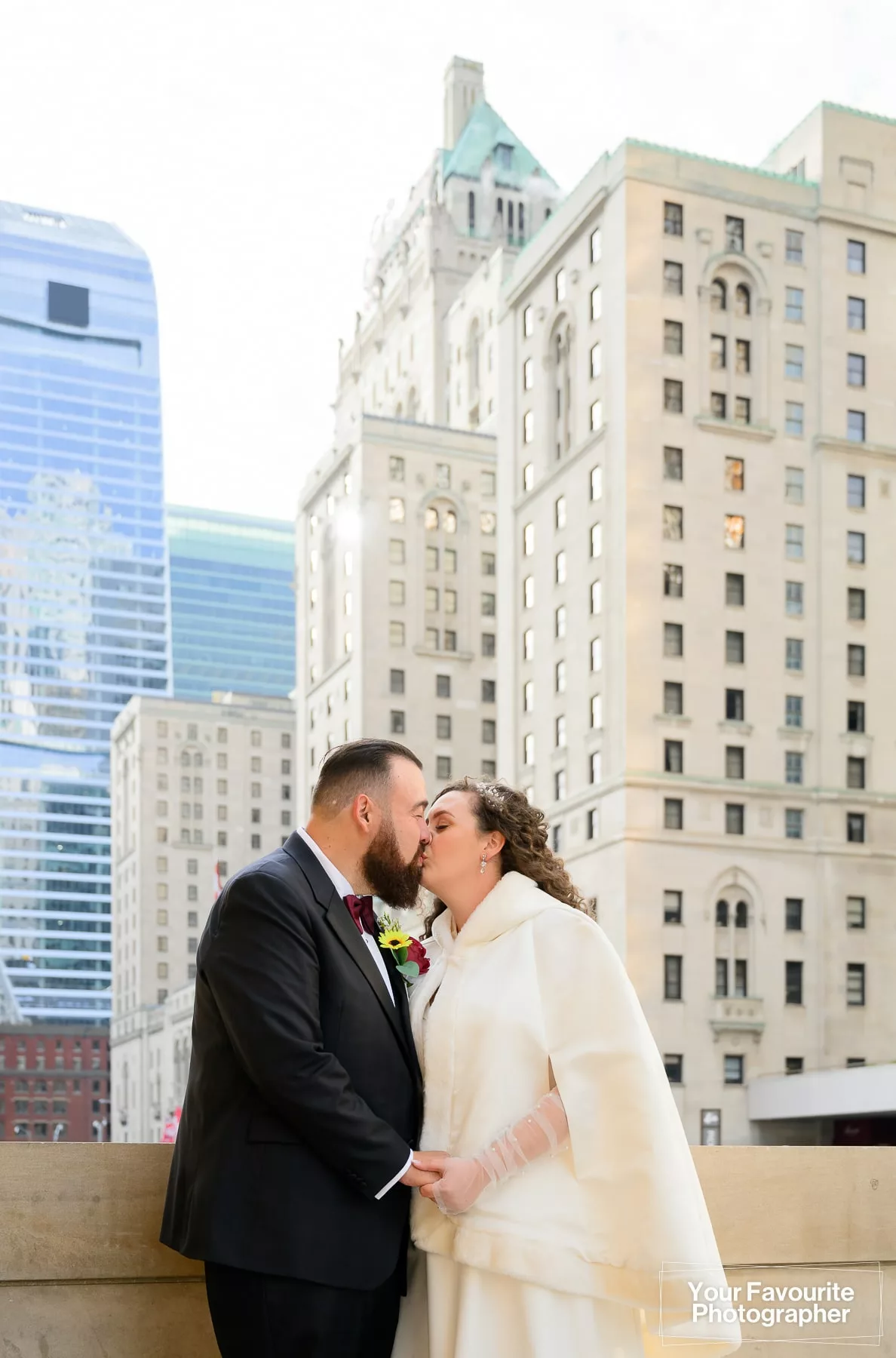 Bride and groom posing in front of Union Station on Front St in downtown Toronto, with the Royal York hotel in the background