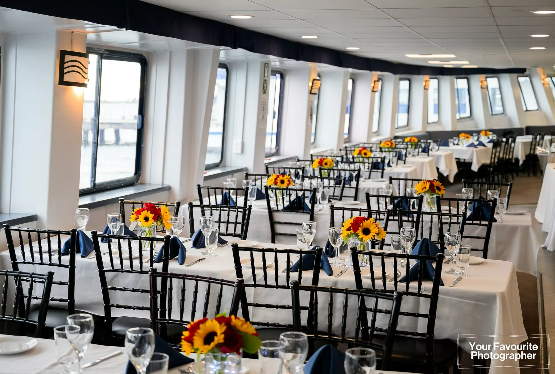 Interior of the Northern Spirit cruise ship set up with tables, chairs, and centrepieces for a wedding
