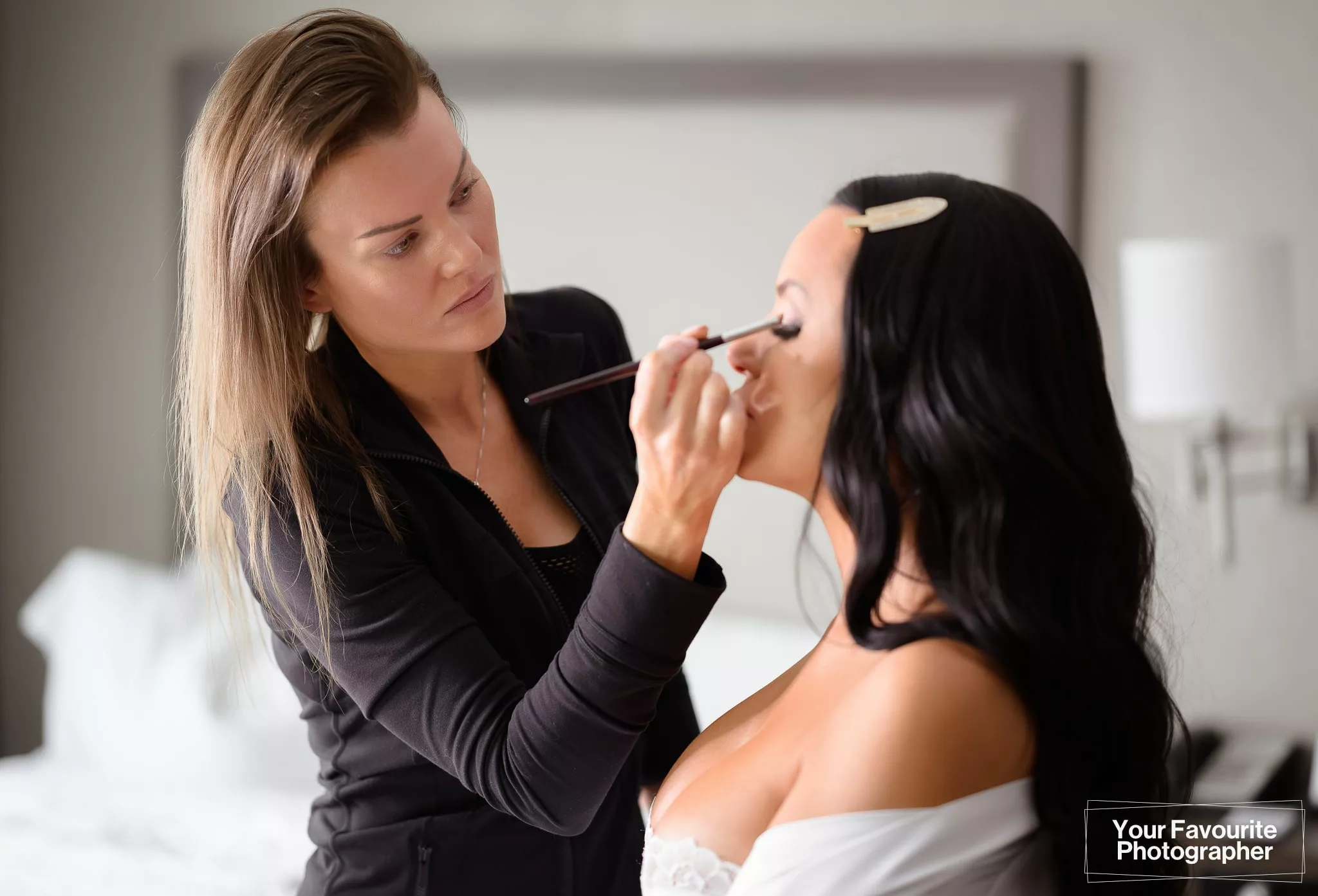 Justine from Violet Noir Artistry applies wedding makeup to Sam at the Hampton Inn and Suites by Hilton Bolton