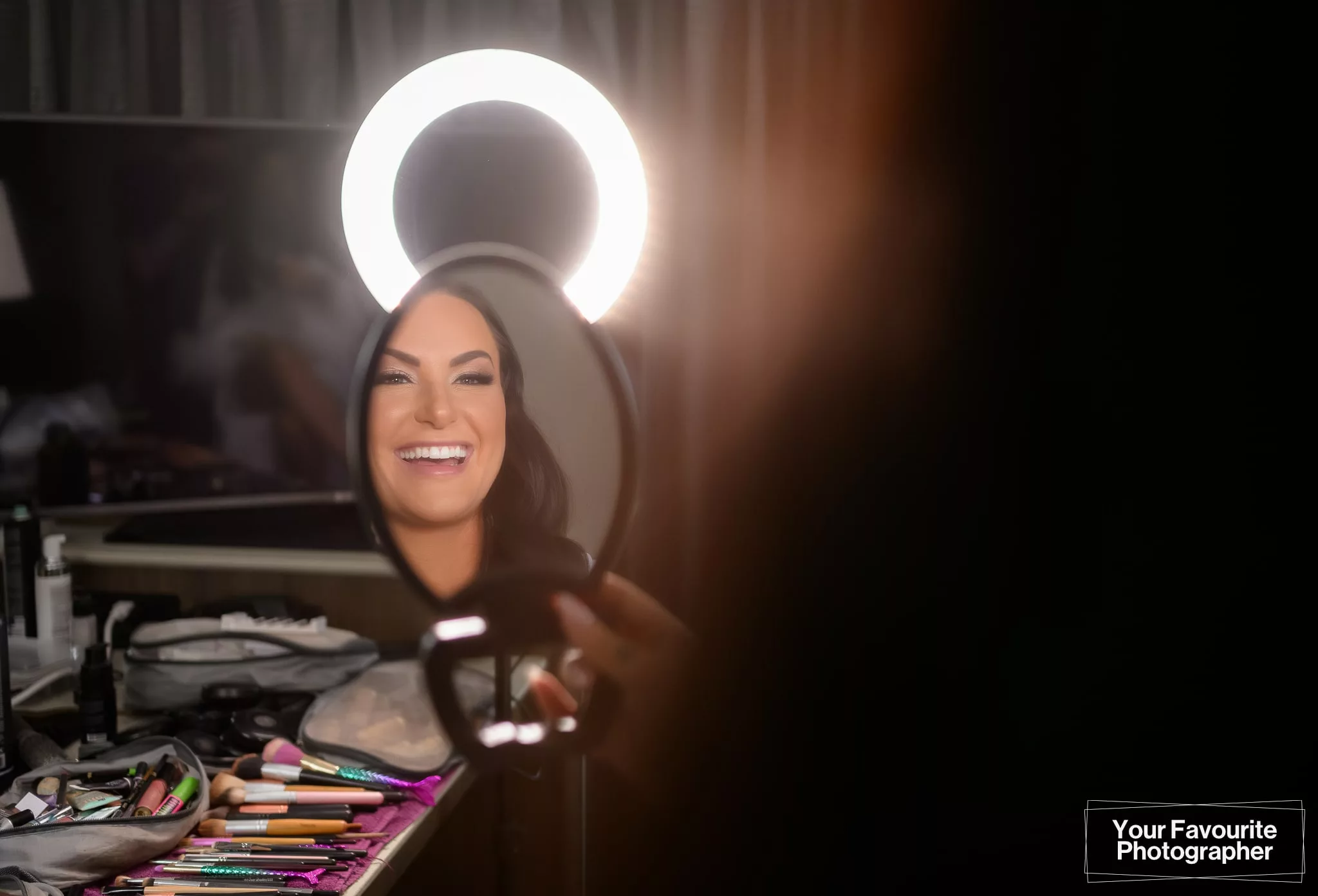 Bride Sam looks in the mirror while getting her makeup done with a ringlight