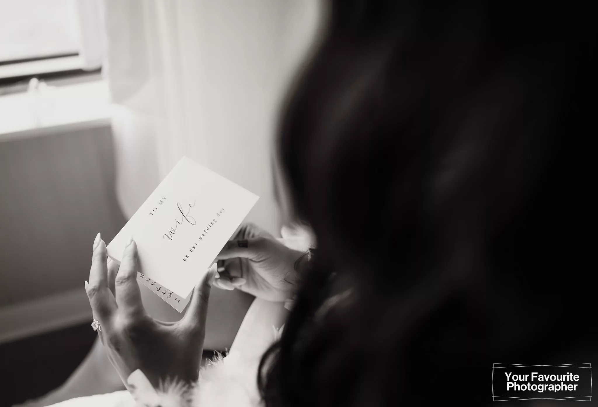 Bride holding "to my wife" card from her future husband on her wedding day