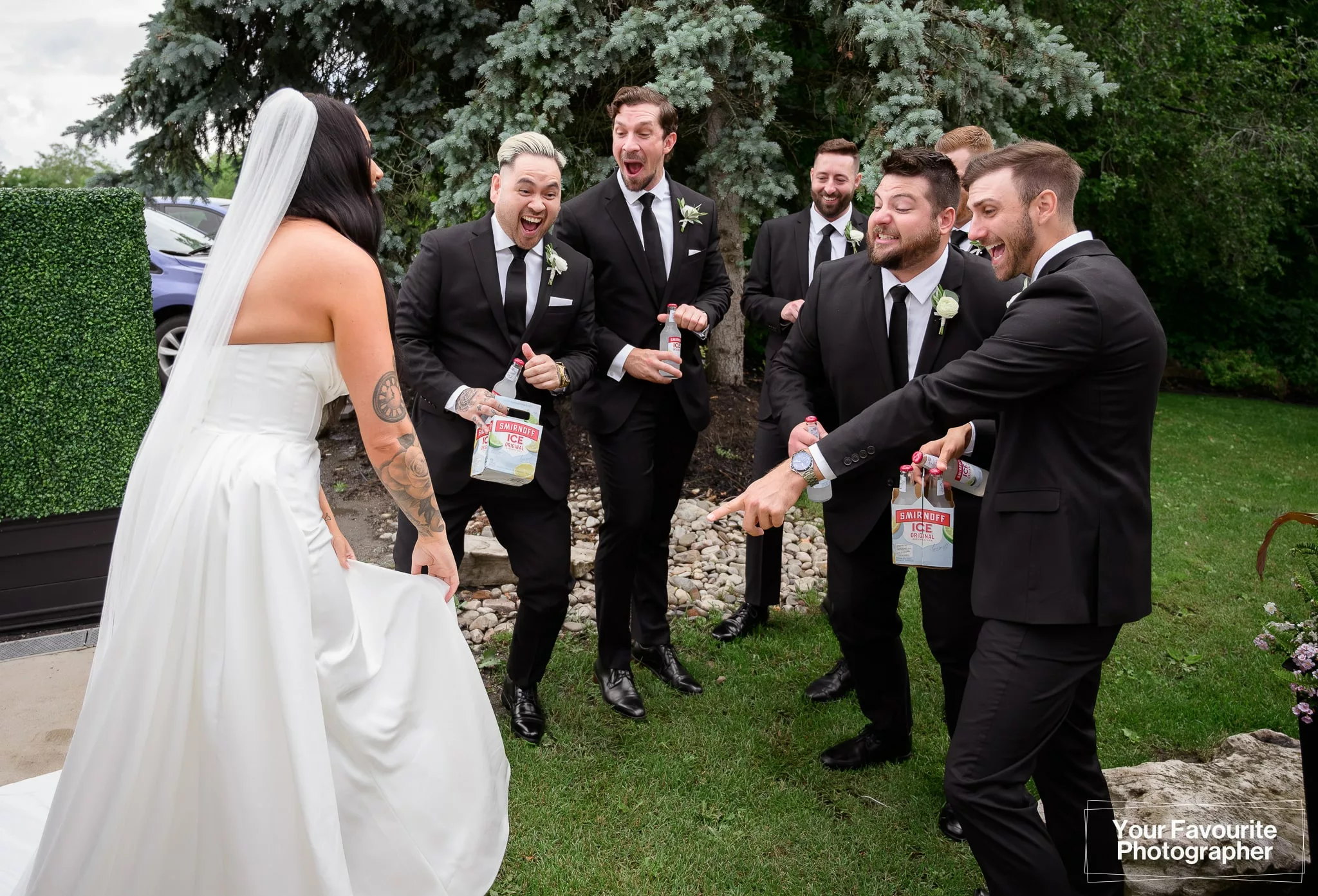 Groomsmen holding Smirnoff Ice bottles reacting to the bride's garter at The Doctor's House wedding venue