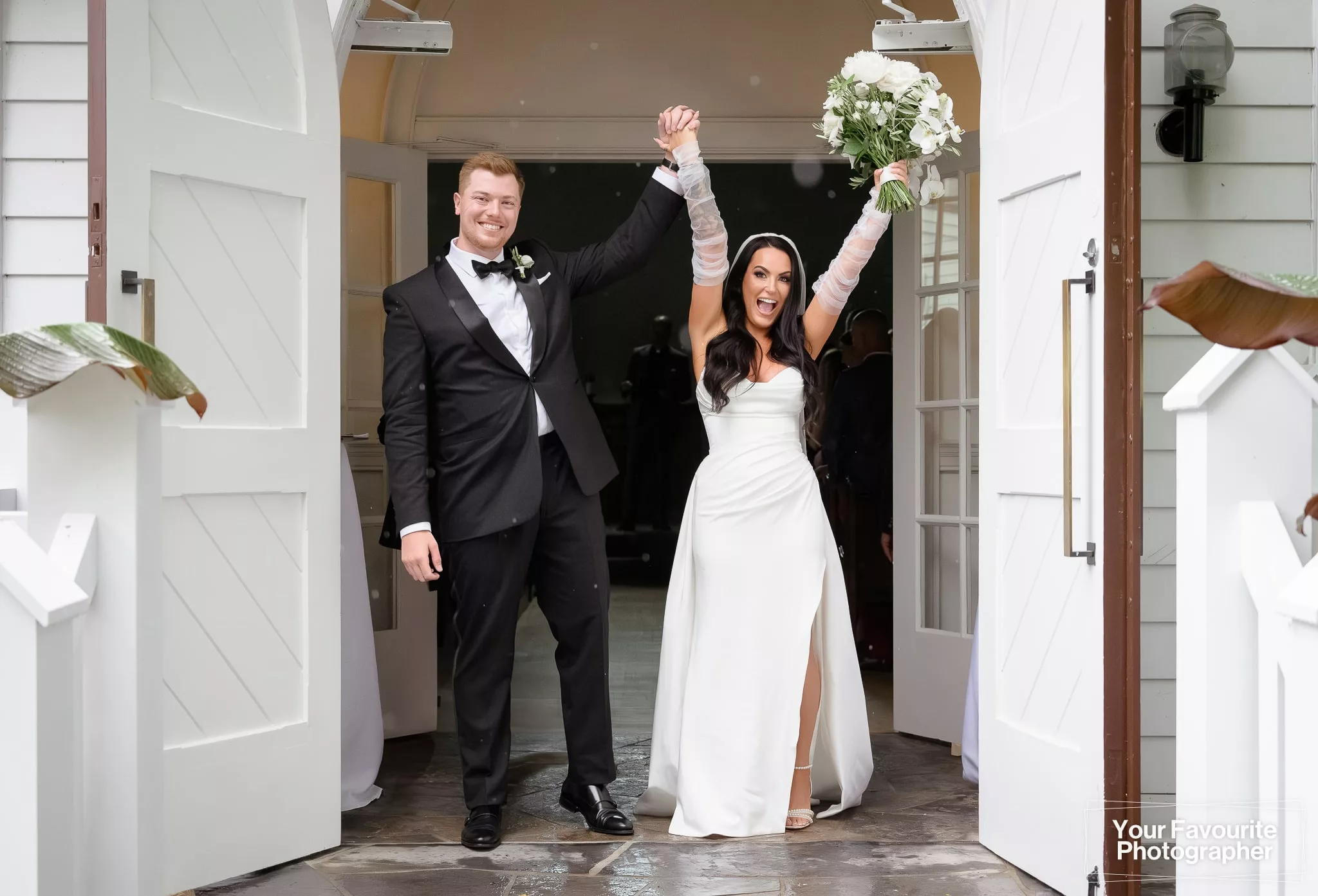At The Doctor's House chapel, Samantha and Robert celebrate their wedding in the doorway with their arms raised